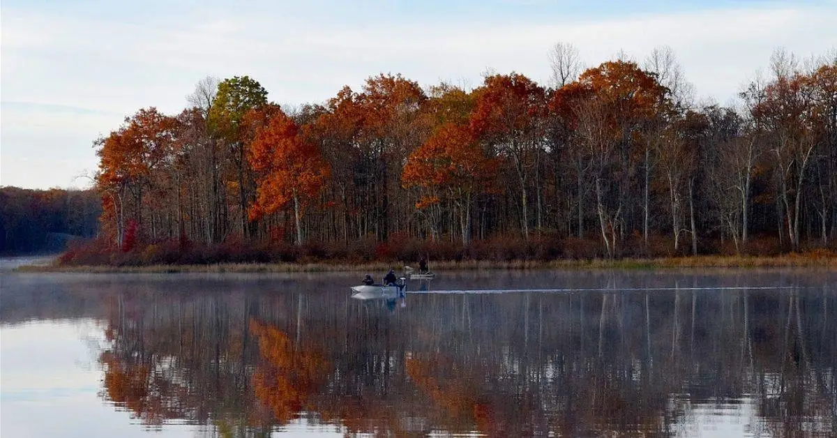 Boat on the lake, fishing for crappie in the fall with colored leaves on the trees