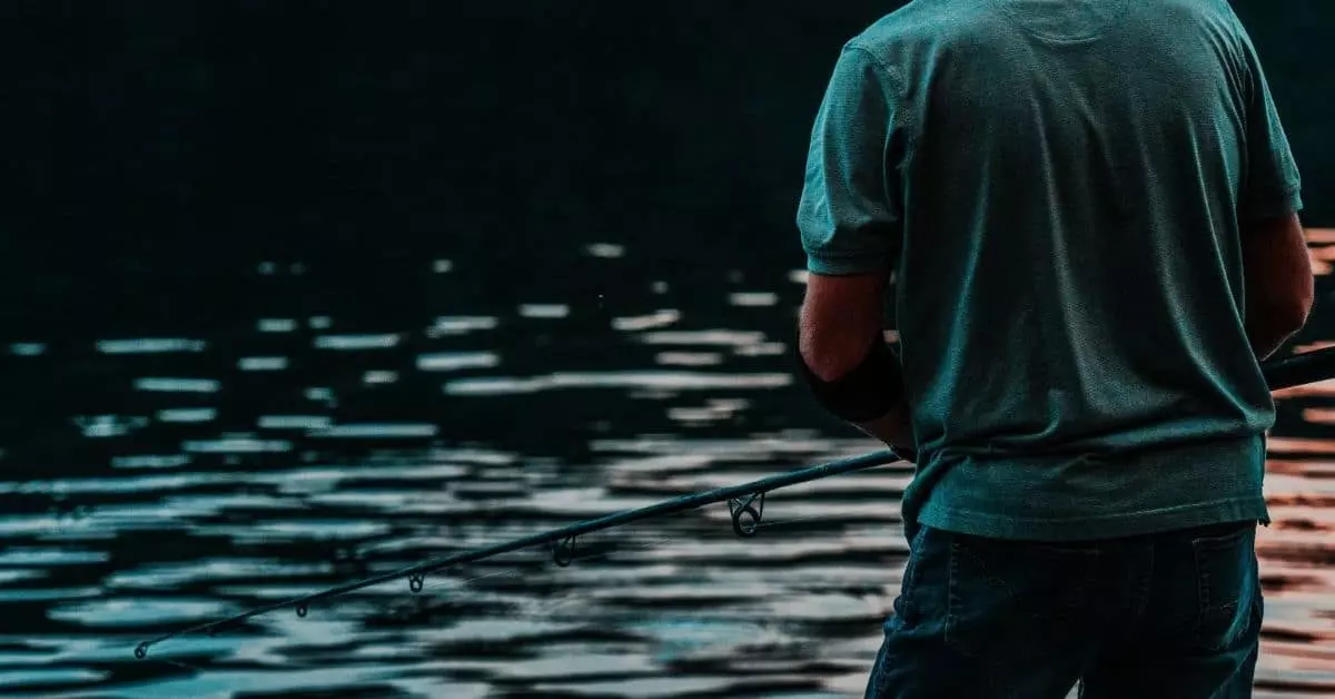 Man in a green shirt fishing at a lake